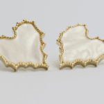 A pair of earrings with gold trim and white background