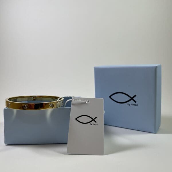 A blue box with a fish on it and a gold bracelet.