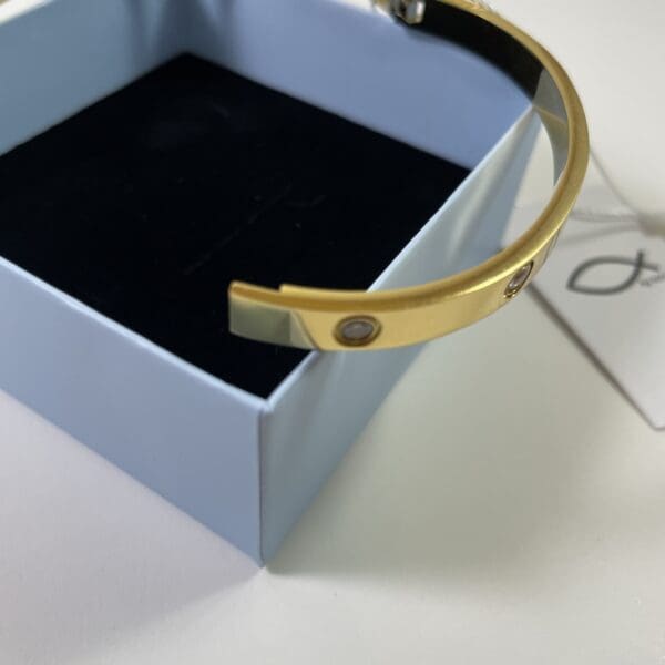 A gold bracelet in its box on top of the table.