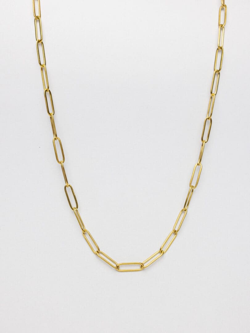 A gold chain necklace is shown on top of a white surface.