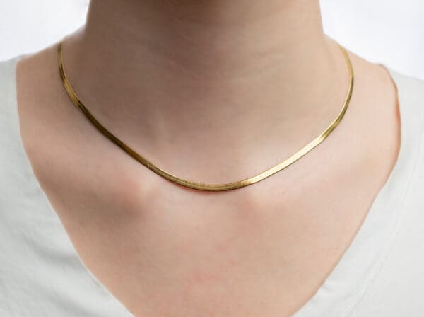 A woman wearing a gold chain necklace.