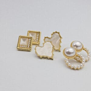 A white table with some gold and pearl earrings