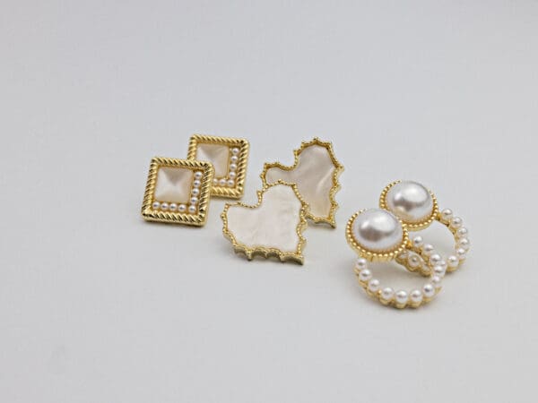 A white table with some gold and pearl earrings