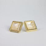 A pair of gold earrings with pearls on top.