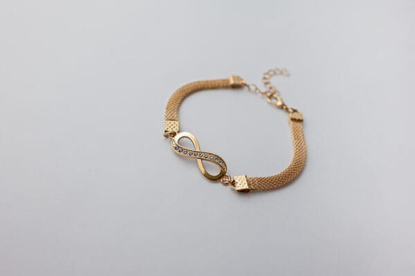 A gold bracelet with an infinity symbol on it.