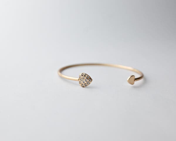 A gold bracelet with two small diamonds on it.