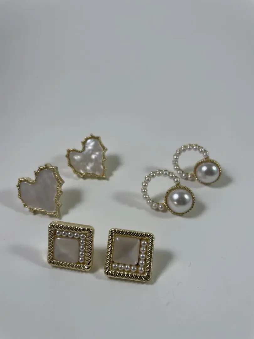 A white table with four pairs of earrings.